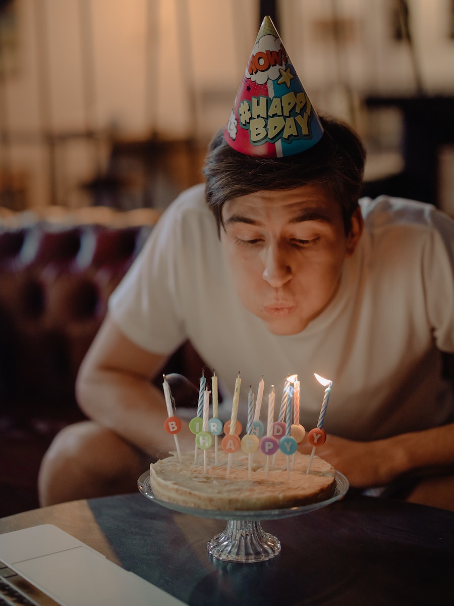 Woman in White Crew Neck T-shirt Sitting in Front of Cake With Candles