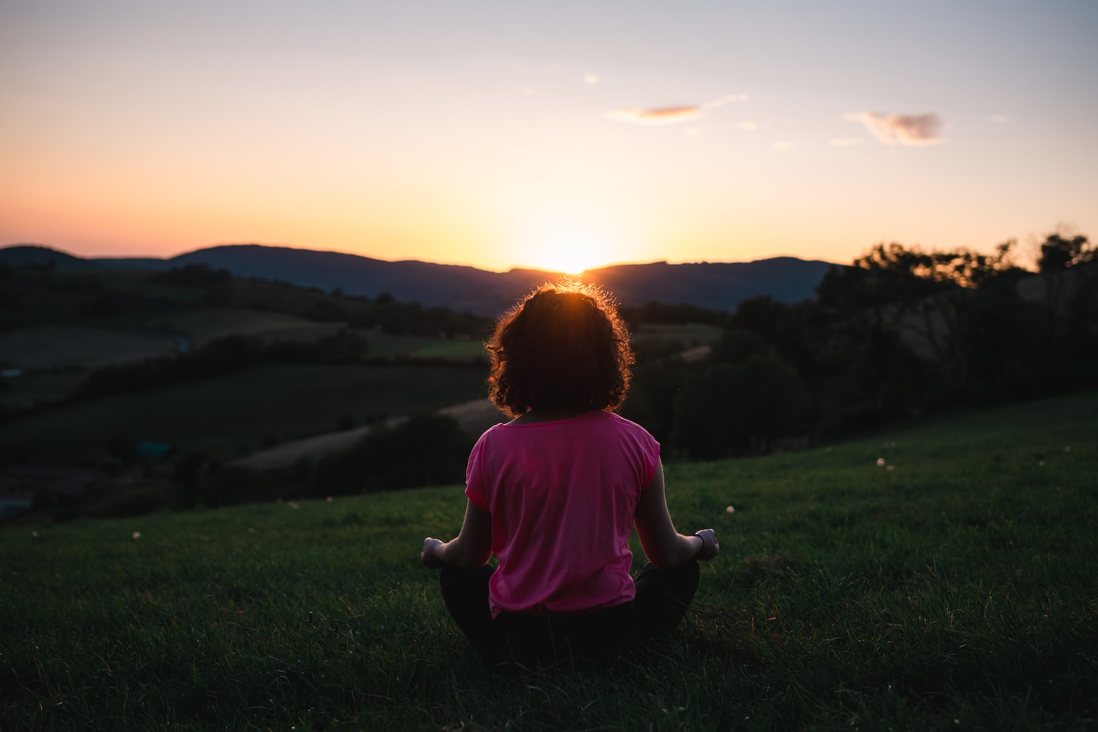 woman squatting in grass during golden hour