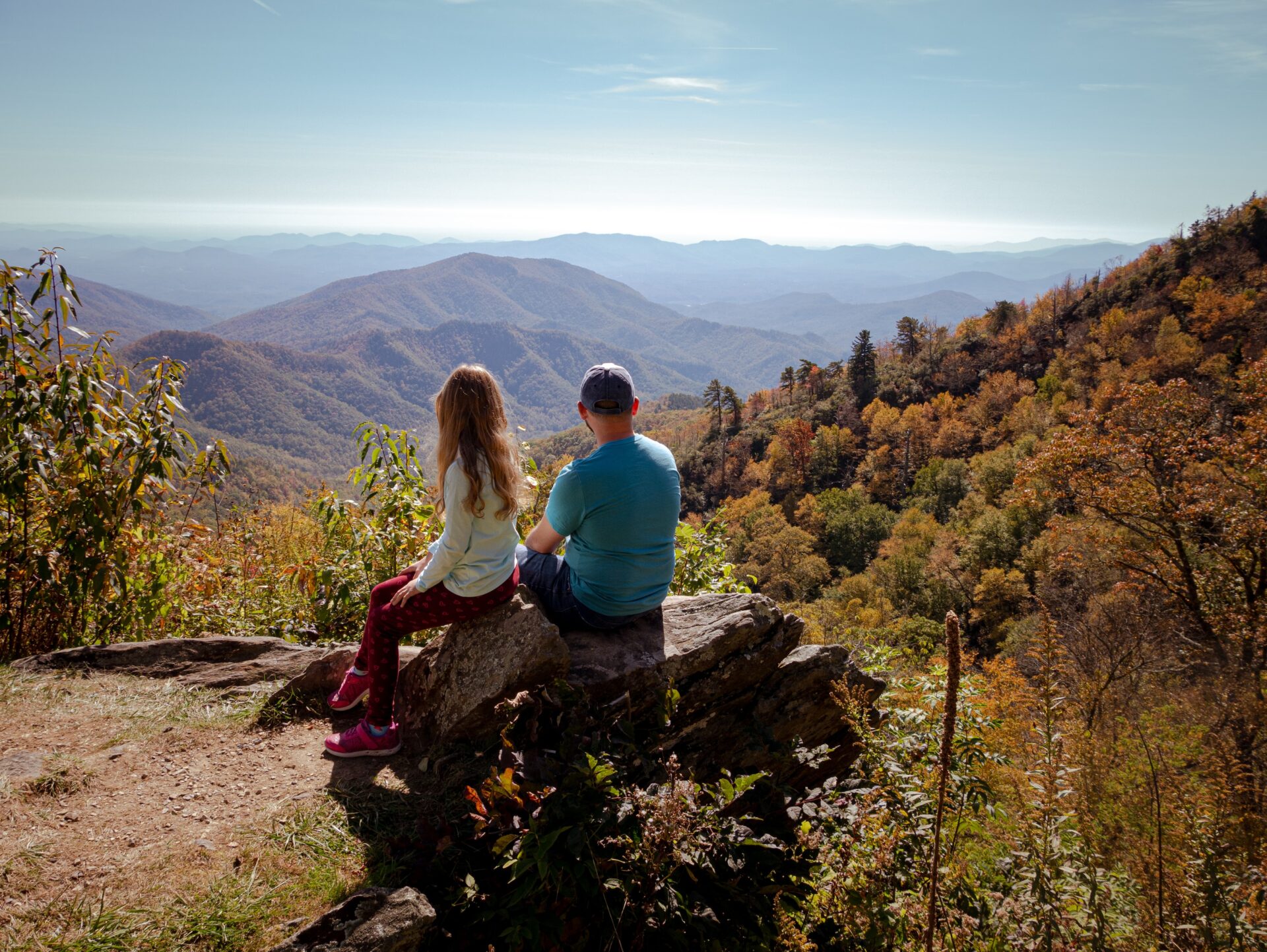 woman in blue long sleeve shirt sitting on rock during daytime