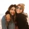 woman hugging other woman while smiling at beach