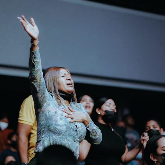 A Woman in Grey Long Sleeves Raising Her Hand While Standing