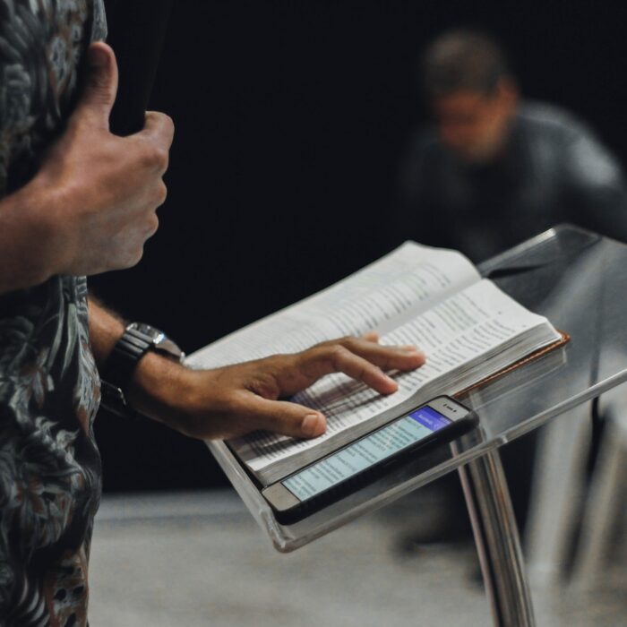 person standing while opening book on stage