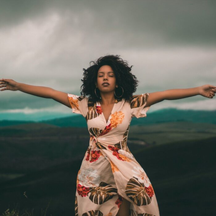 Woman in White and Red Floral Dress Standing on Green Grass Field