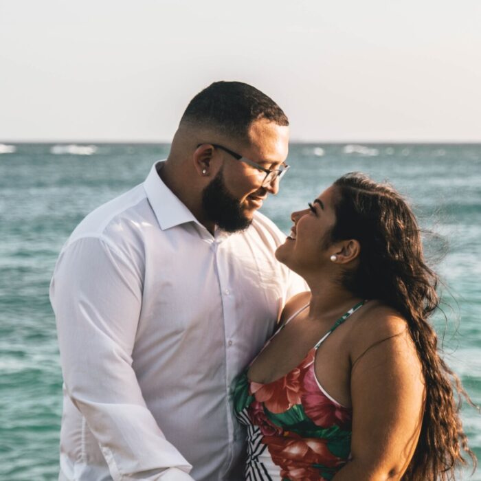 Photo of Happy Couple Looking at Each Other With Ocean in the Background