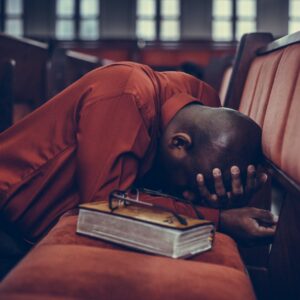 man in orange top beside eyeglasses on brown book