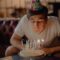 Woman in White Crew Neck T-shirt Sitting in Front of Cake With Candles