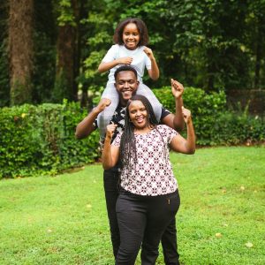 a man and two women holding a child on their shoulders