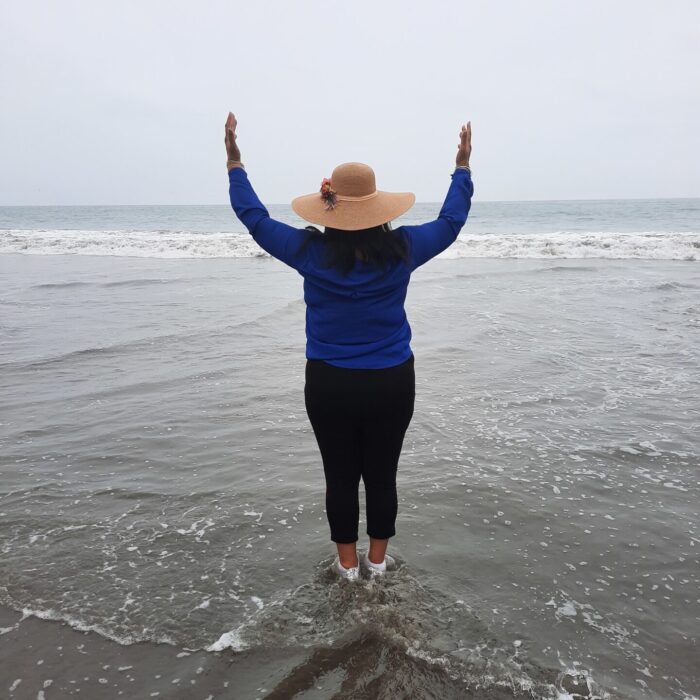 Woman Standing on the Beach Raising Her Hands