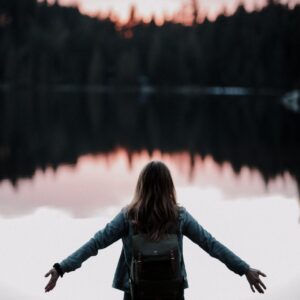 woman standing while facing on body of water