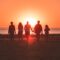 silhouette photo of five person walking on seashore during golden hour