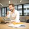 Depth of Field Photo of Man Sitting on Chair While Holding Cup in Front of Table