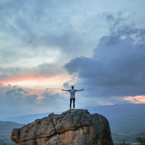 man standing on top of rock mountain during golden hour