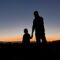 silhouette of man and woman standing on beach during sunset