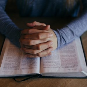 man holding his hands on open book