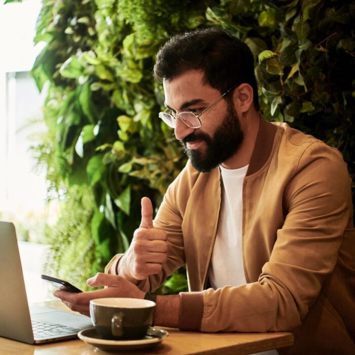 man in brown jacket sitting at a table looking at laptop