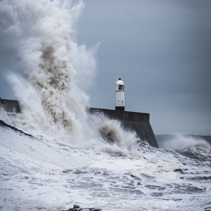 big waves crashing on lighthouse during daytime