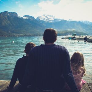 man and woman sitting on brown wooden dock during daytime