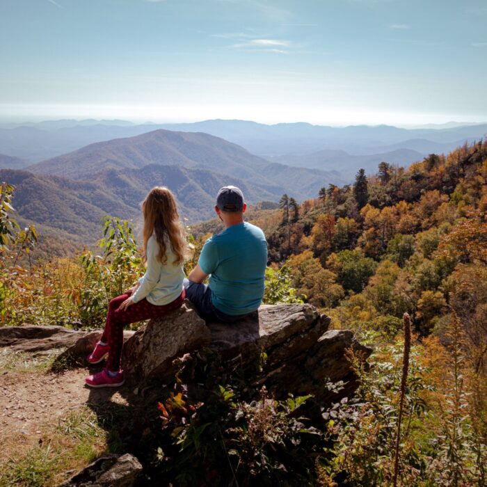 woman in blue long sleeve shirt sitting on rock during daytime