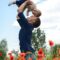 man in blue long sleeve shirt carrying baby in white onesie