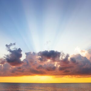 man raising his arms on sea under black clouds