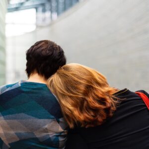 a woman rests her head on another person's shoulder