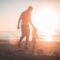 man holding girl heading towards sea