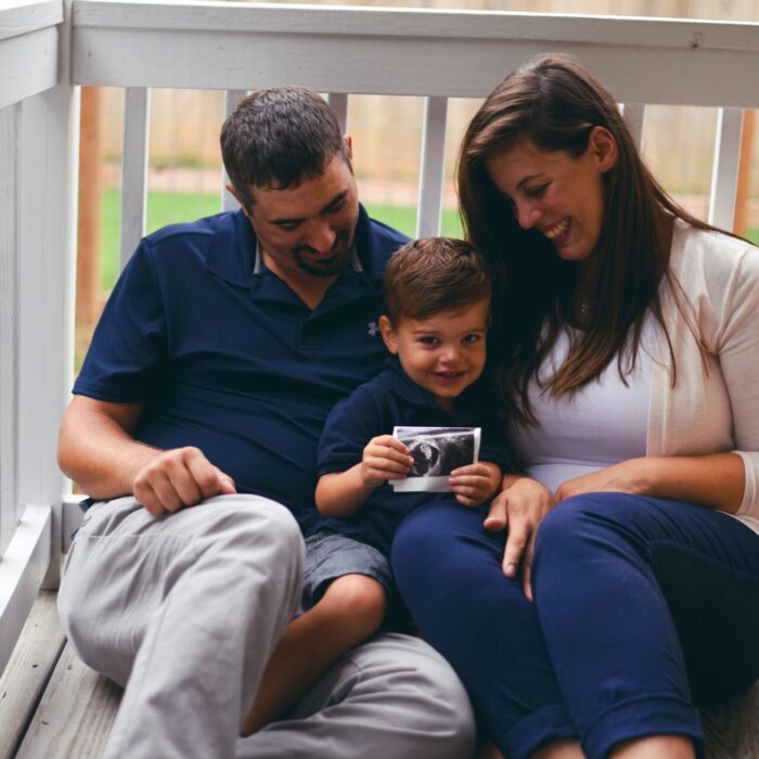 boy between man and woman during daytime