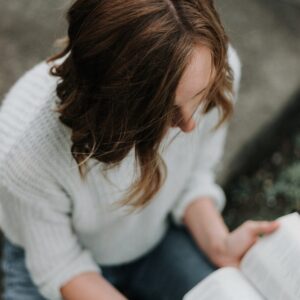 woman sitting on floor while reading book