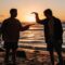 close-up photo of two men shaking hands near beach at sunset