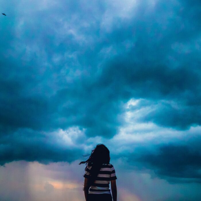 person wearing black and white stripe shirt across blue clouds