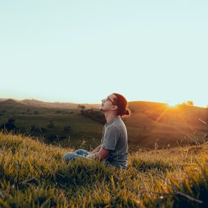 man in white shirt sitting on green grass field during sunset