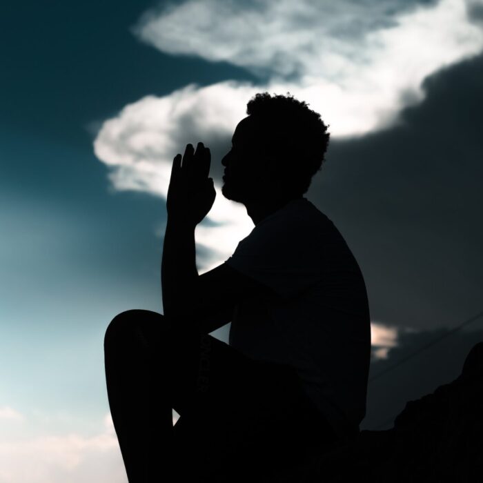 silhouette of man sitting on rock during daytime