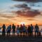 people standing on shore during golden hour