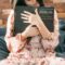 woman in white and red floral dress holding black book