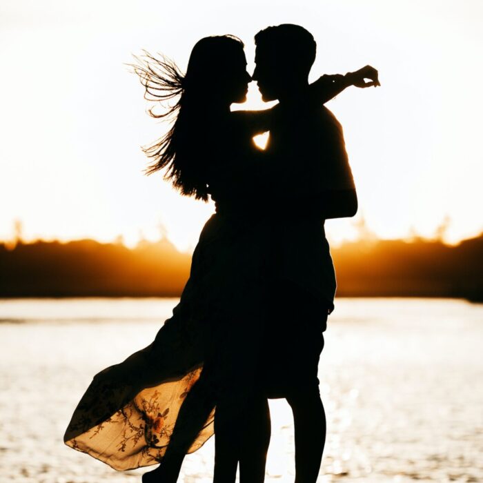 silhouette of woman standing on beach during sunset