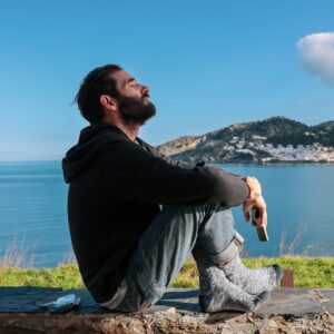 man sitting on a concrete bench overlooking the beach