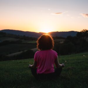 woman squatting in grass during golden hour