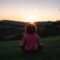 woman squatting in grass during golden hour