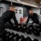 man in black long sleeve shirt and black pants carrying black dumbbell